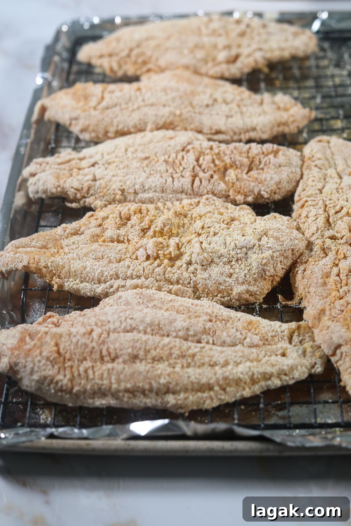 Crispy Oven-Baked Catfish with Garlic and Lemon 6 breaded southern catfish on a baking sheet before going in the oven.
