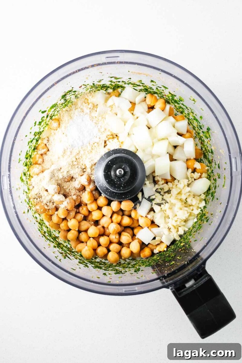 Crispy Baked Falafel Using Canned Chickpeas 7 Canned chickpeas and further falafel ingredients in a food processor bowl viewed from above.