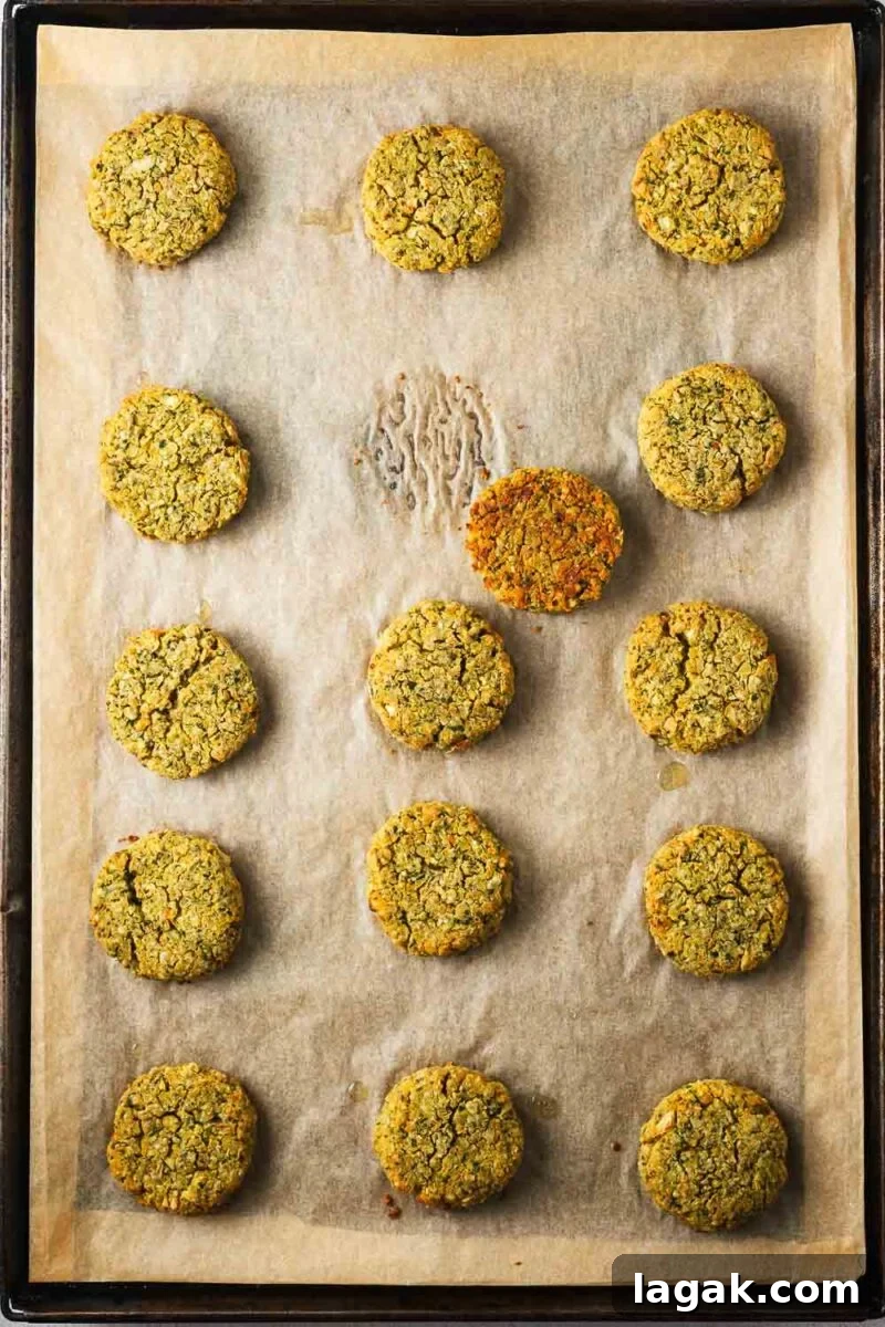 Crispy Baked Falafel Using Canned Chickpeas 10 A baking sheet with baked falafel and one falafel flipped over to reveal a golden brown bottom.