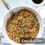 Blackstone fried rice in white bowl with spoon and side of soy sauce.