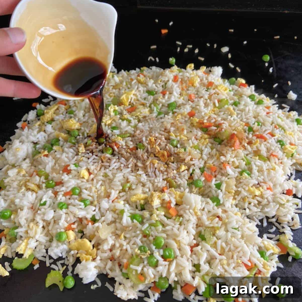 Crispy Blackstone Fried Rice Recipe for Restaurant-Style Flavor 7 Hand pouring soy sauce over fried rice.