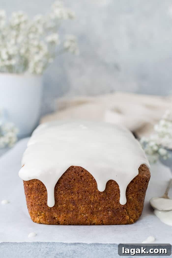 Moist Vegan Carrot Cake Loaf Recipe for Every Occasion 4 Unsliced vegan carrot cake with lemon glaze on baking parchment.