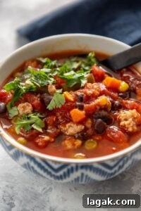 turkey soup with veggies in a white and blue bowl