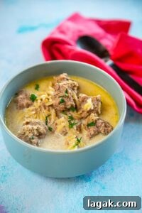 creamy meatball soup in the slow cooker served in a bowl on blue table next to spoon and red napkin