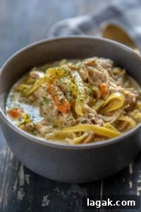 Slow Cooker Creamy Chicken Noodle Soup in a gray bowl topped with parsley