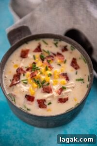 metal bowl filled with chicken corn chowder topped with chives and bacon