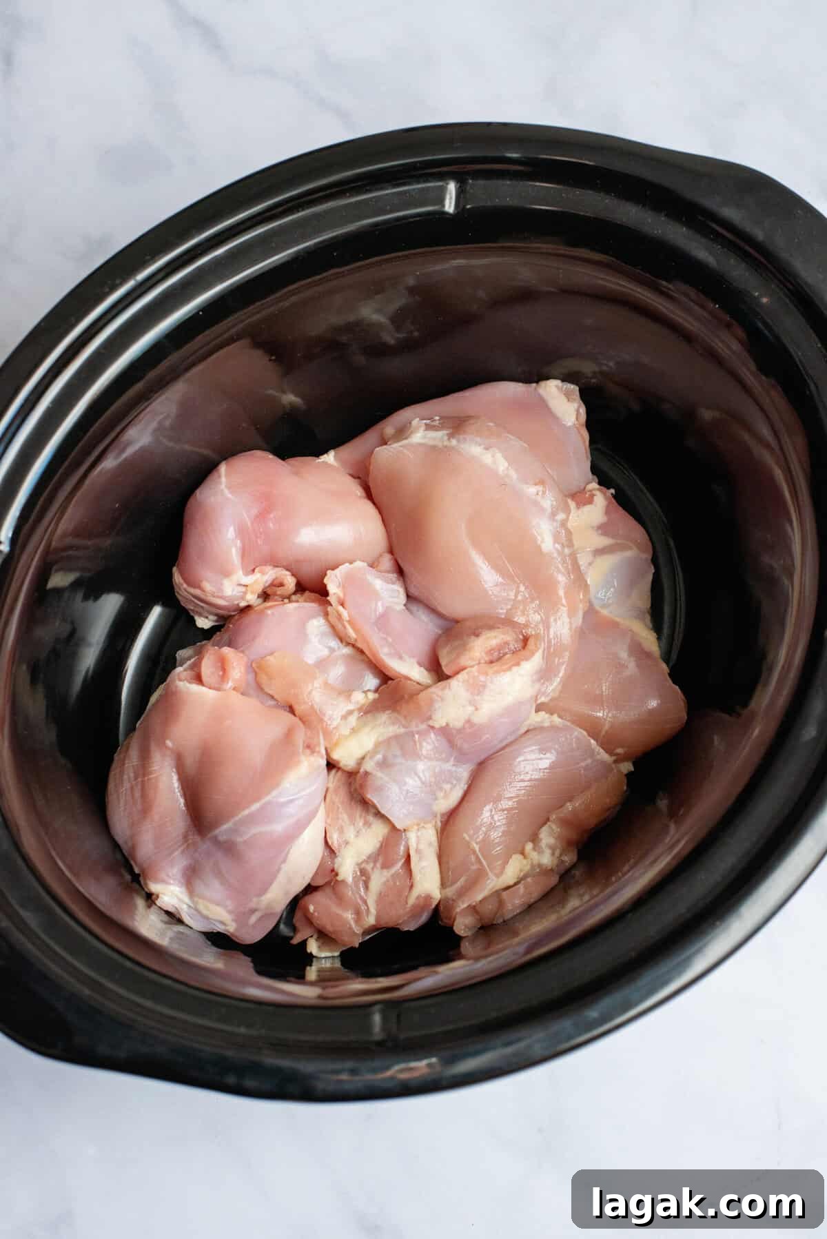 Mississippi Chicken Served Over Creamy Mashed Sweet Potatoes 5 Raw chicken thighs placed in the bottom of a slow cooker, ready to be seasoned and cooked for Mississippi chicken.