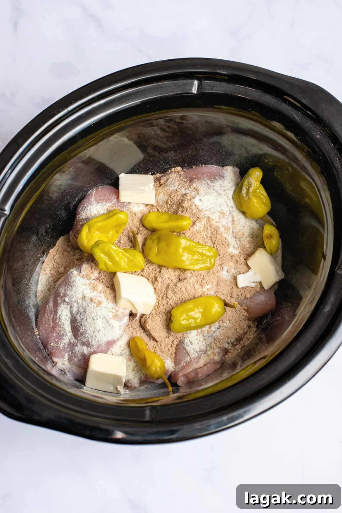Mississippi Chicken Served Over Creamy Mashed Sweet Potatoes 7 Raw Mississippi chicken ingredients in a slow cooker, including seasoned chicken thighs topped with pepperoncini peppers and chunks of butter, ready to be slow-cooked for a flavorful, tender dish.