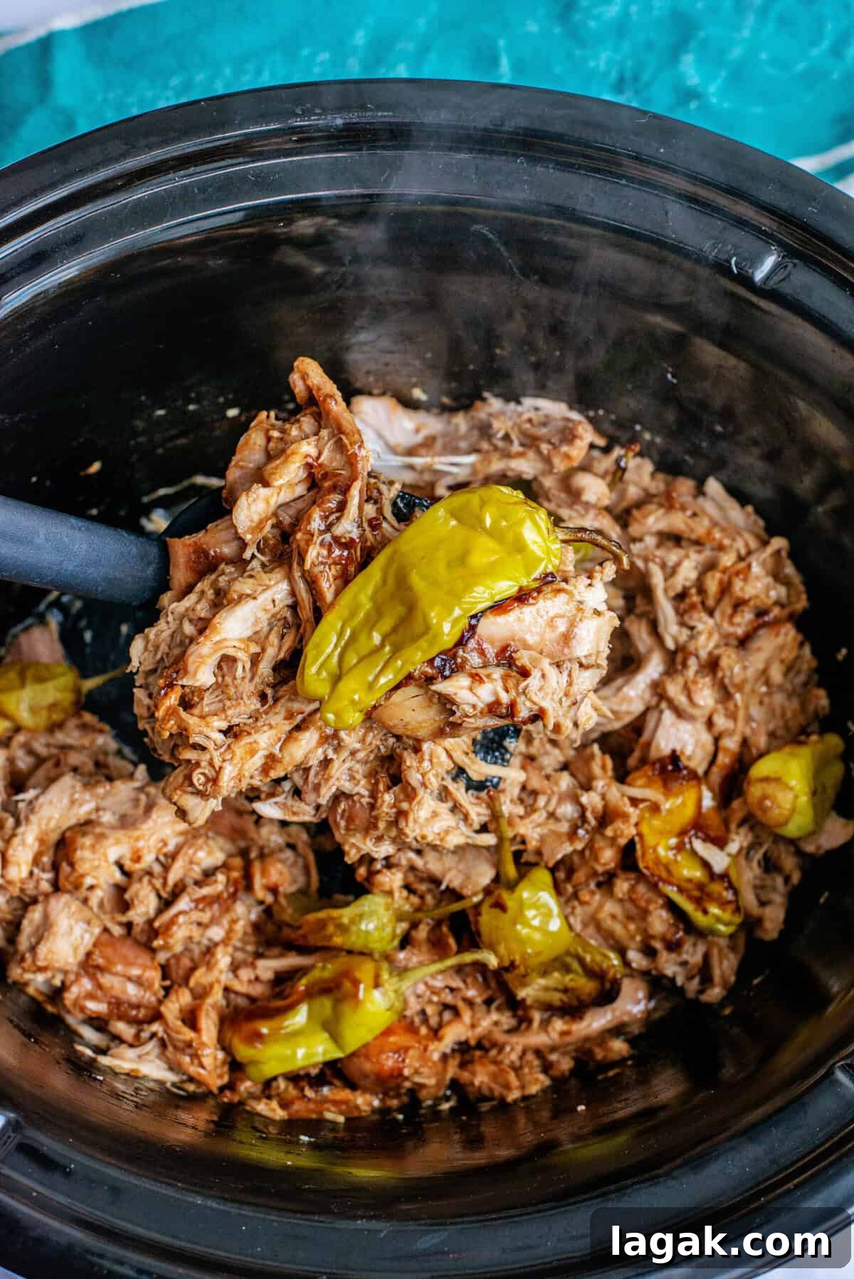 Mississippi Chicken Served Over Creamy Mashed Sweet Potatoes 9 Steaming shredded Mississippi chicken in a slow cooker, mixed with tender pepperoncini peppers and savory juices, with a serving spoon scooping up the flavorful mixture.