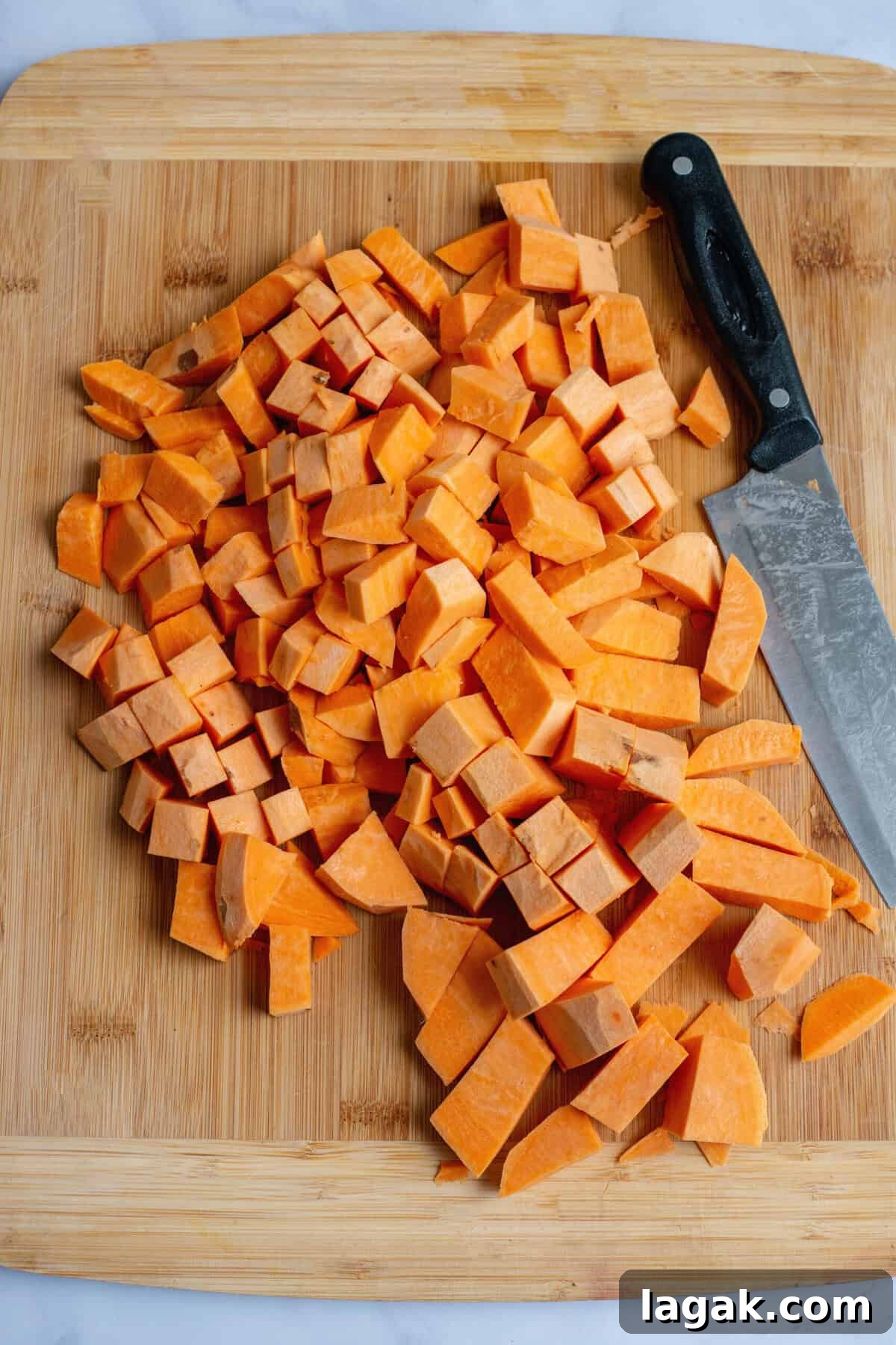 Mississippi Chicken Served Over Creamy Mashed Sweet Potatoes 10 Pile of freshly chopped sweet potatoes on a wooden cutting board with a large chef's knife beside them, ready for cooking.