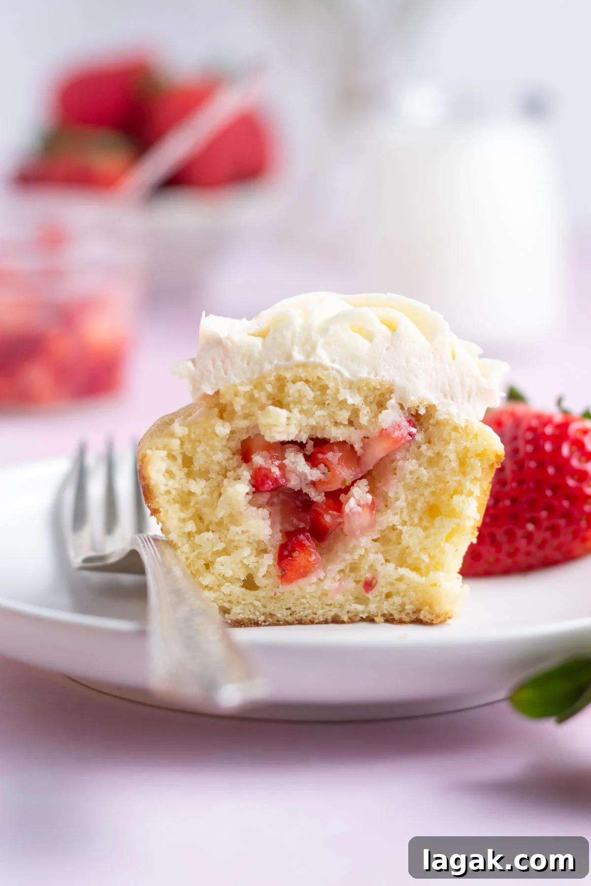 Strawberry filled cupcake on a plate with a fork.