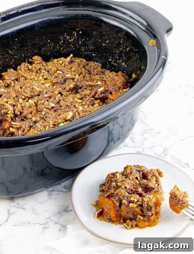 crockpot of Slow Cooker Sweet Potato Casserole and a white plate with a single portion
