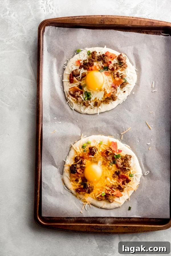 Breakfast pizzas assembled with eggs. Breakfast pizzas assembled on a baking tray with eggs added.