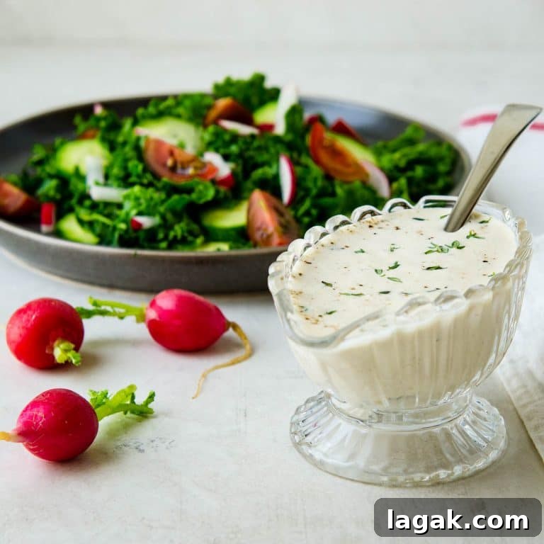 Creamy Garlic Dressing Recipe for Salads and Marinades 8 creamy garlic dressing in a glass carafe with a green salad.
