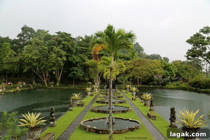 Water palace with palm trees down the middle of the pont and statues 