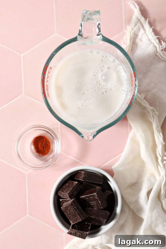 Ingredients to make vegan hot chocolate in bowls on a pink tiled surface with a white linen