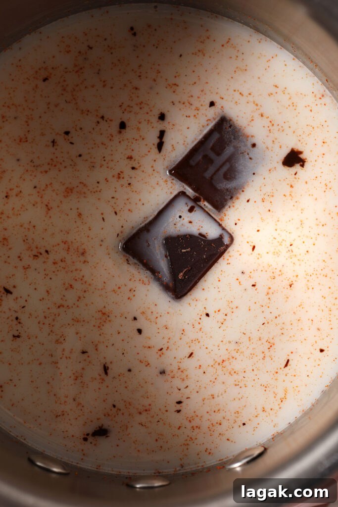 Close up of chocolate cubes in a saucepan with milk and cayenne