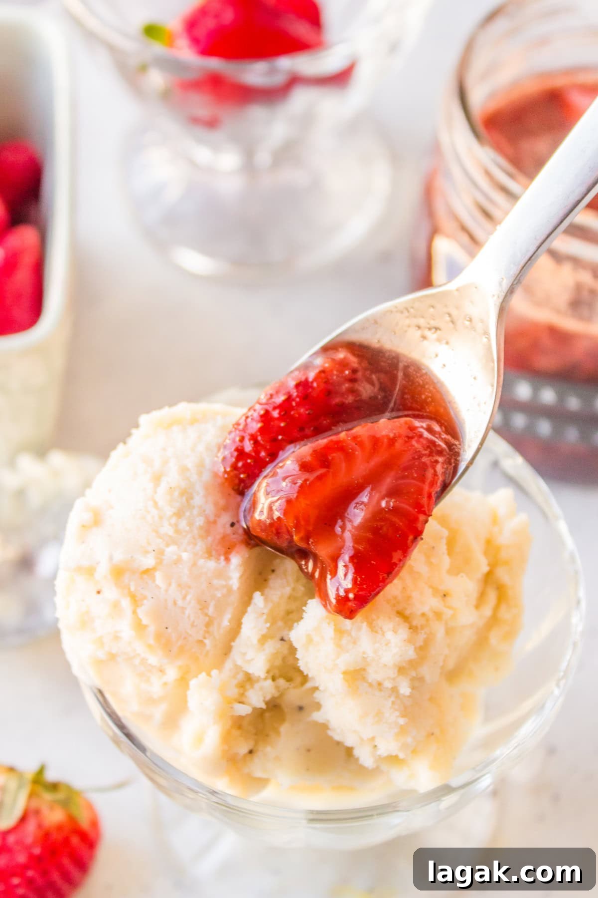 spooning balsamic strawberry sauce onto vanilla ice cream in dish