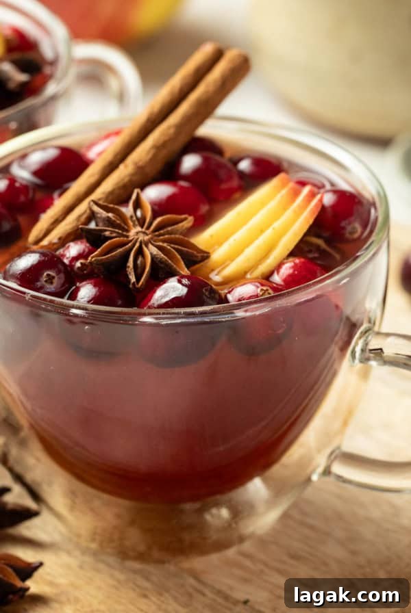 Two mugs of Christmas wassail next to cinnamon sticks and star anise.