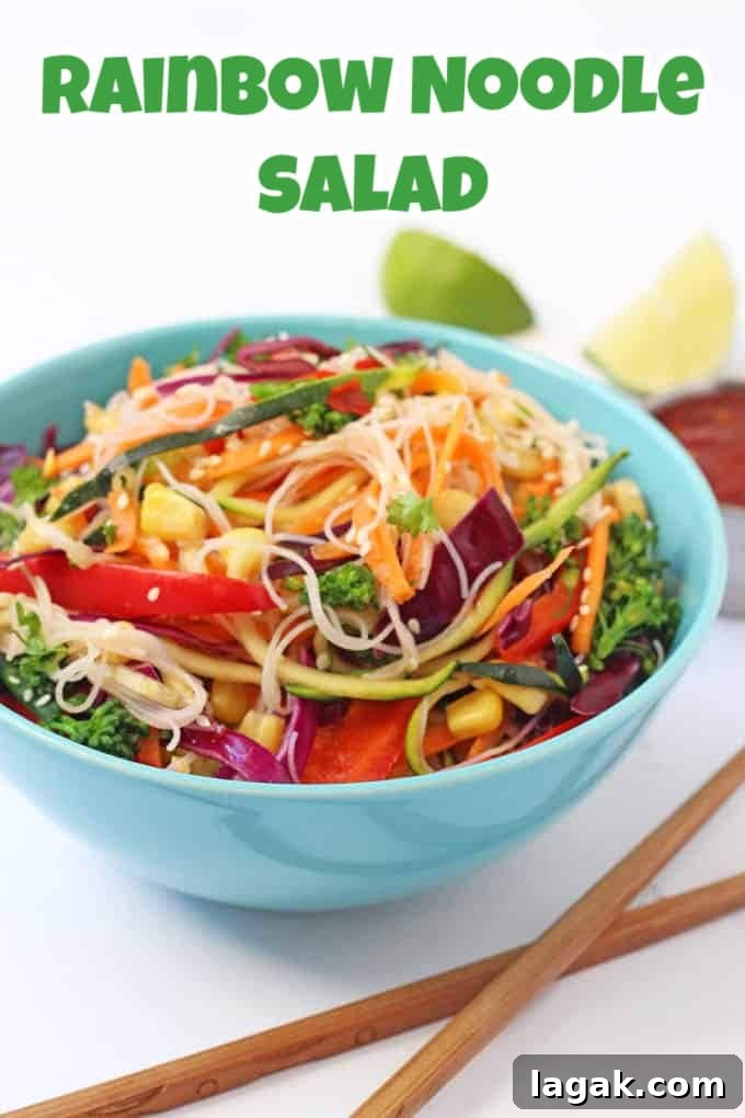 Rainbow Noddle Salad served in a brightly coloured blue bowl with a set of wooden chopsticks in the foreground.