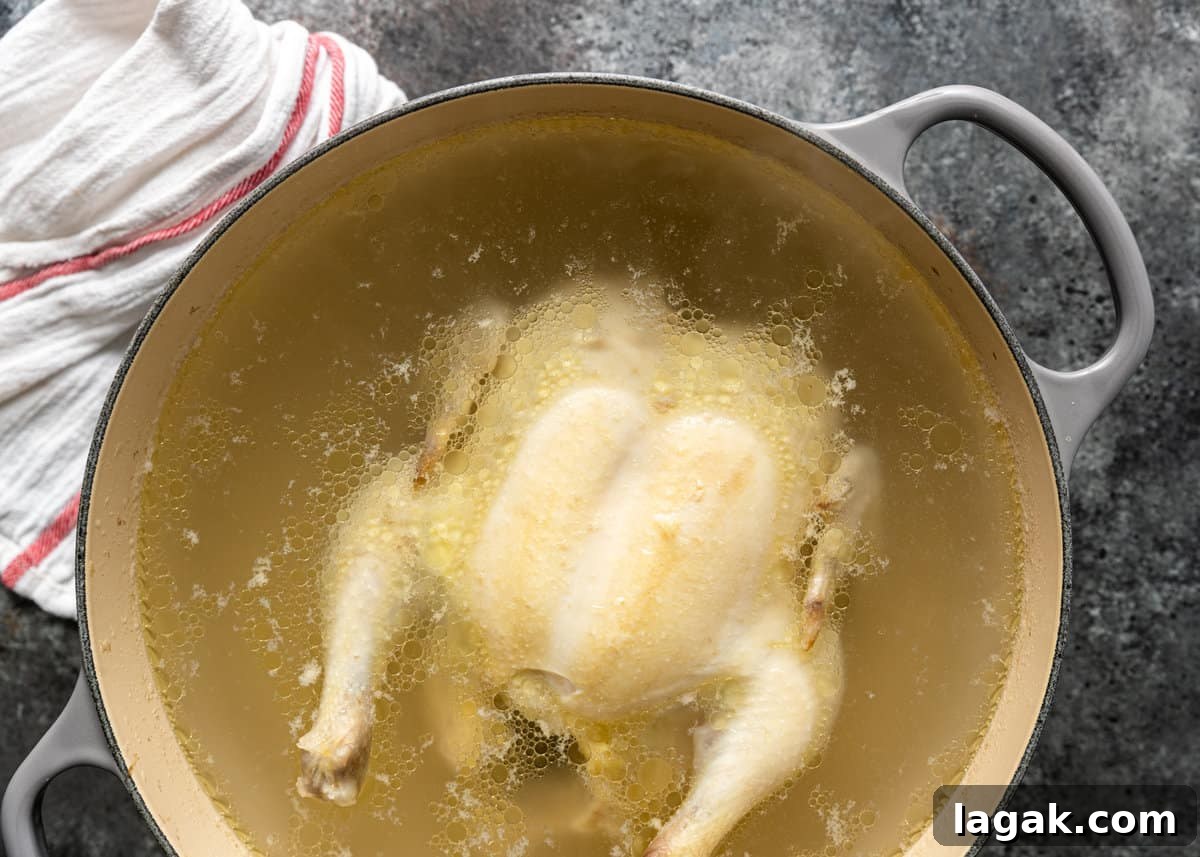 overhead: whole chicken in a pot of water on counter with white linen off to side