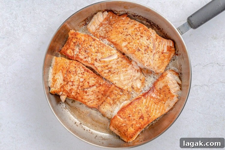 Salmon slices in a large skillet with melted butter.