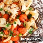 Roasted cauliflower and carrots on a brown plate with fresh parsley on top.