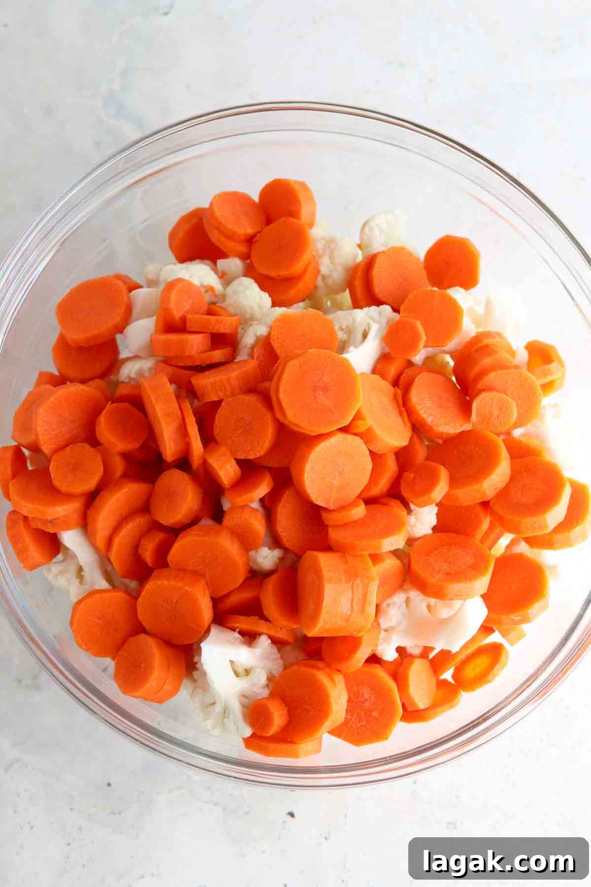 Coined carrots and cauliflower florets in a glass bowl.