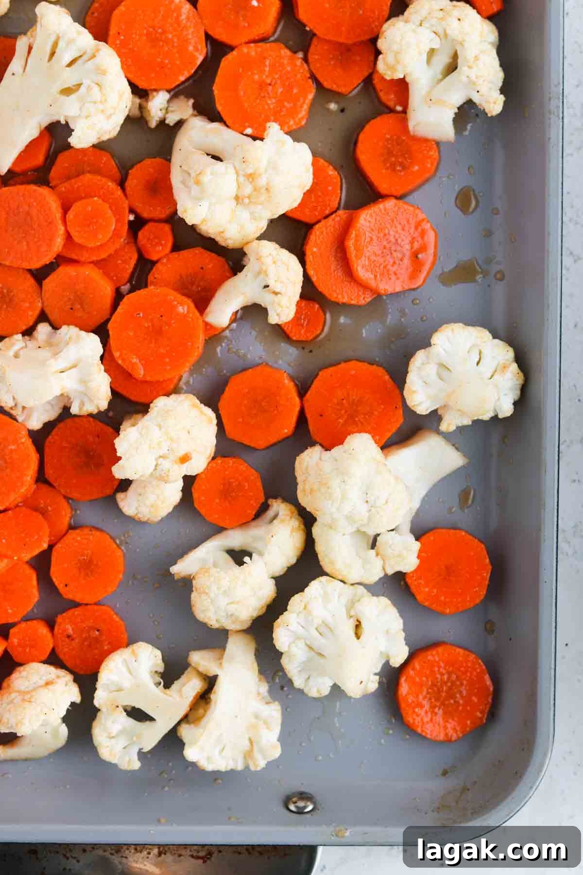Cauliflower, and coined carrots laid out on a sheet pan.