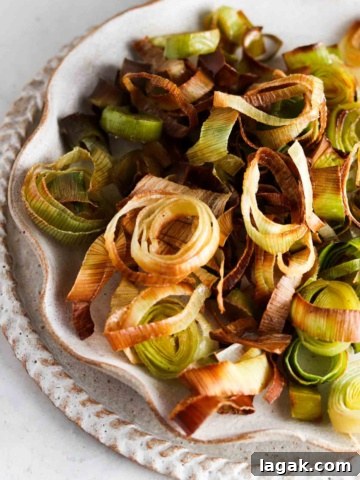 Roasted leeks on a ruffled edge plate on the counter top.