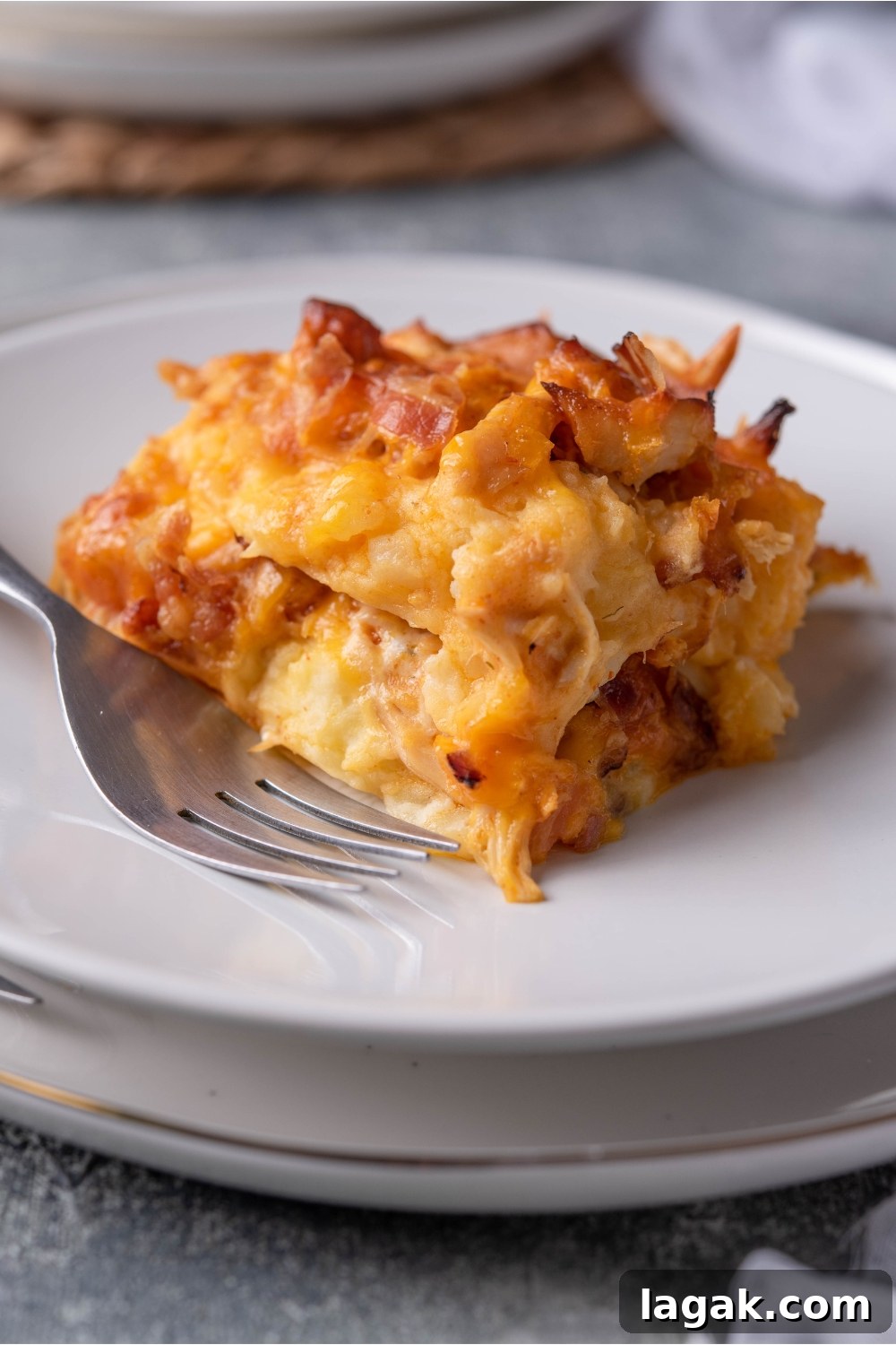 White plate with a serving of buffalo chicken casserole and a fork on the plate.
