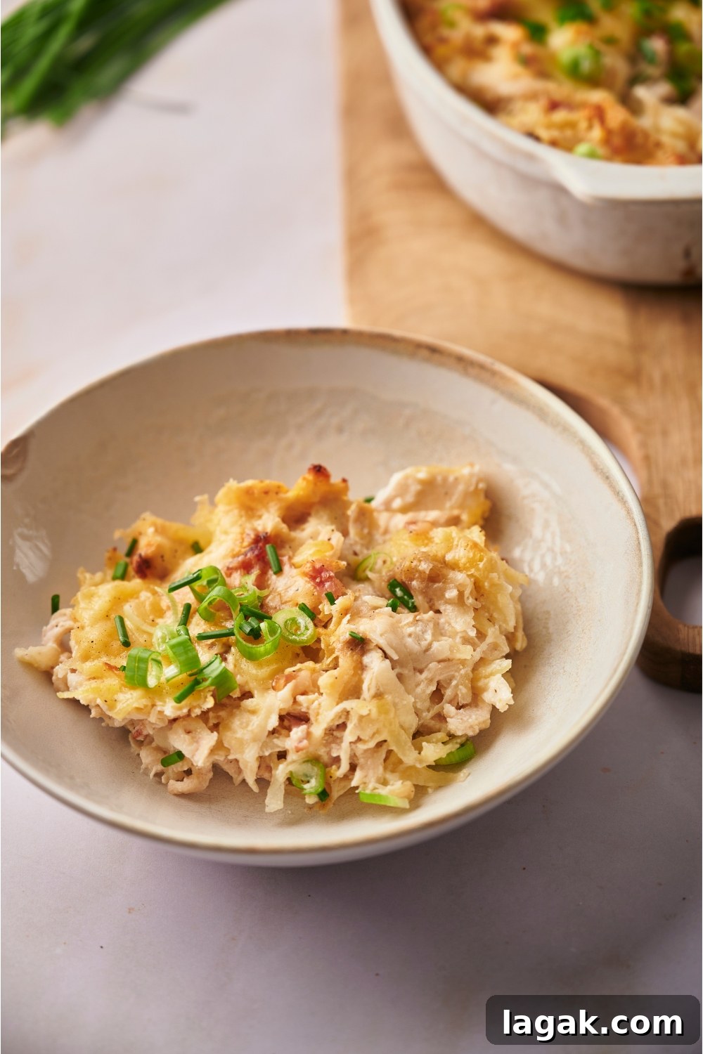 A white bowl with a serving of chicken hashbrown casserole.