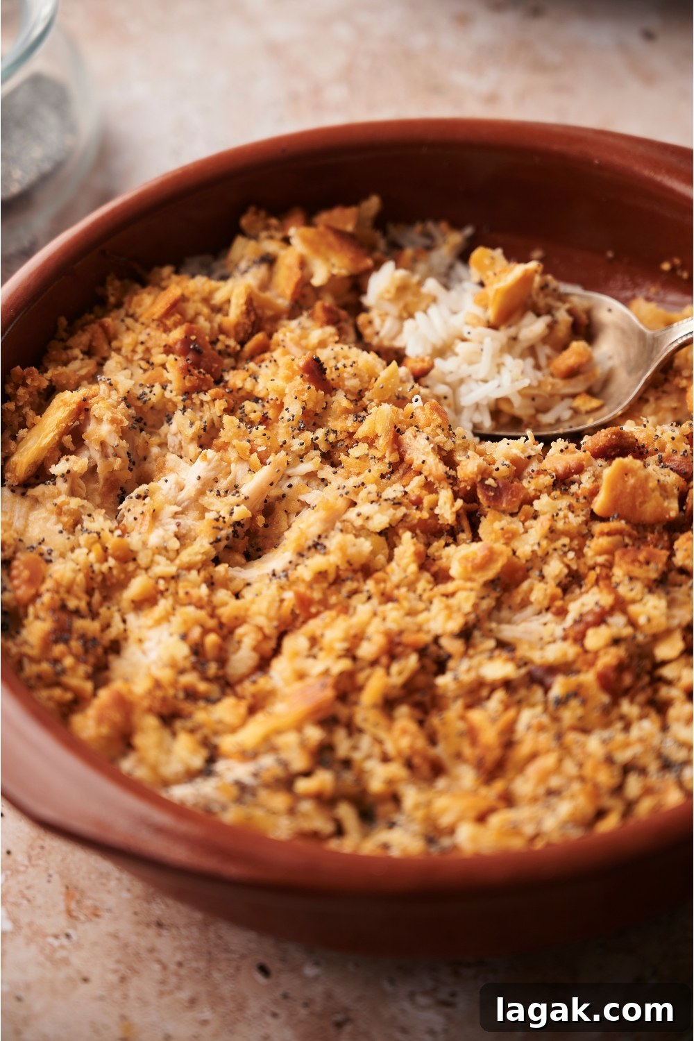 Poppy seed chicken casserole in a red casserole dish with a spoon in the dish.