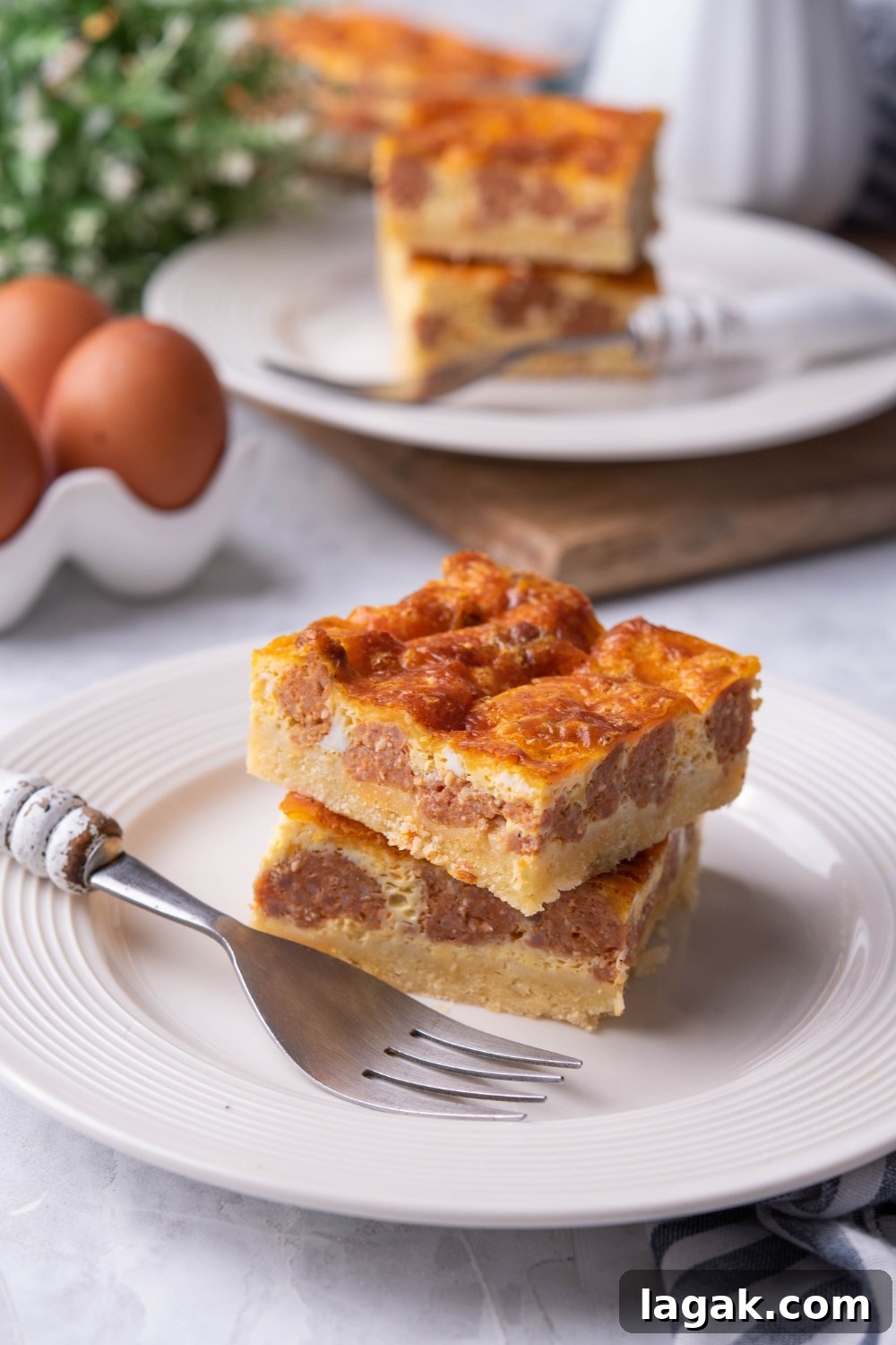 A plate with two squares of casserole and a fork laying next to them.