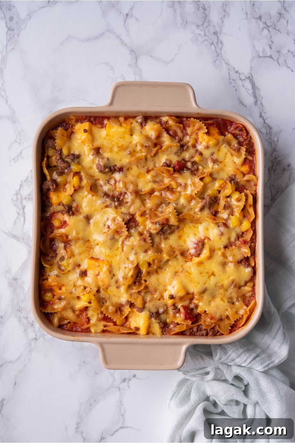 Melted shredded cheese on top of a sloppy joe casserole in a baking dish.