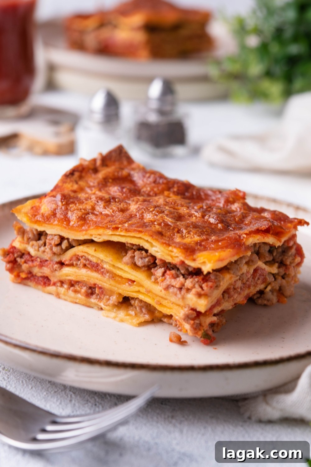 A slice of ground beef enchilada casserole on a white plate.