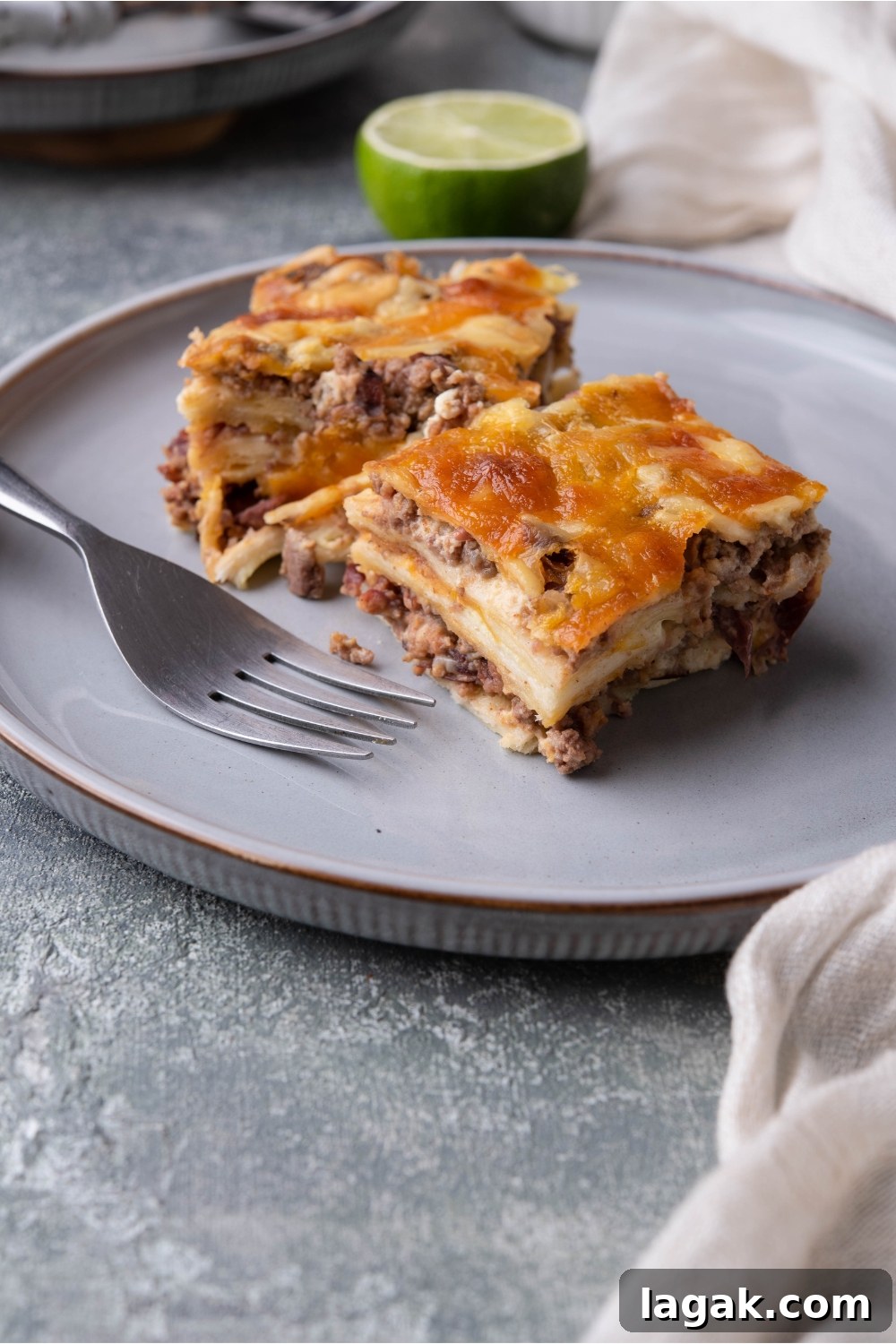 Two slices of burrito casserole on a blue plate with a fork on the plate.