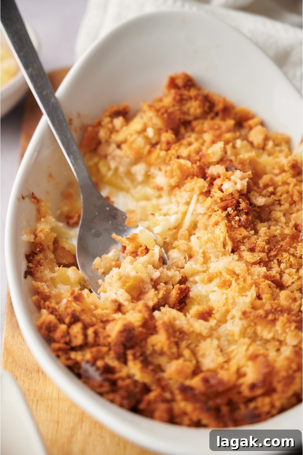 pineapple casserole in a casserole dish with a serving spoon in the dish