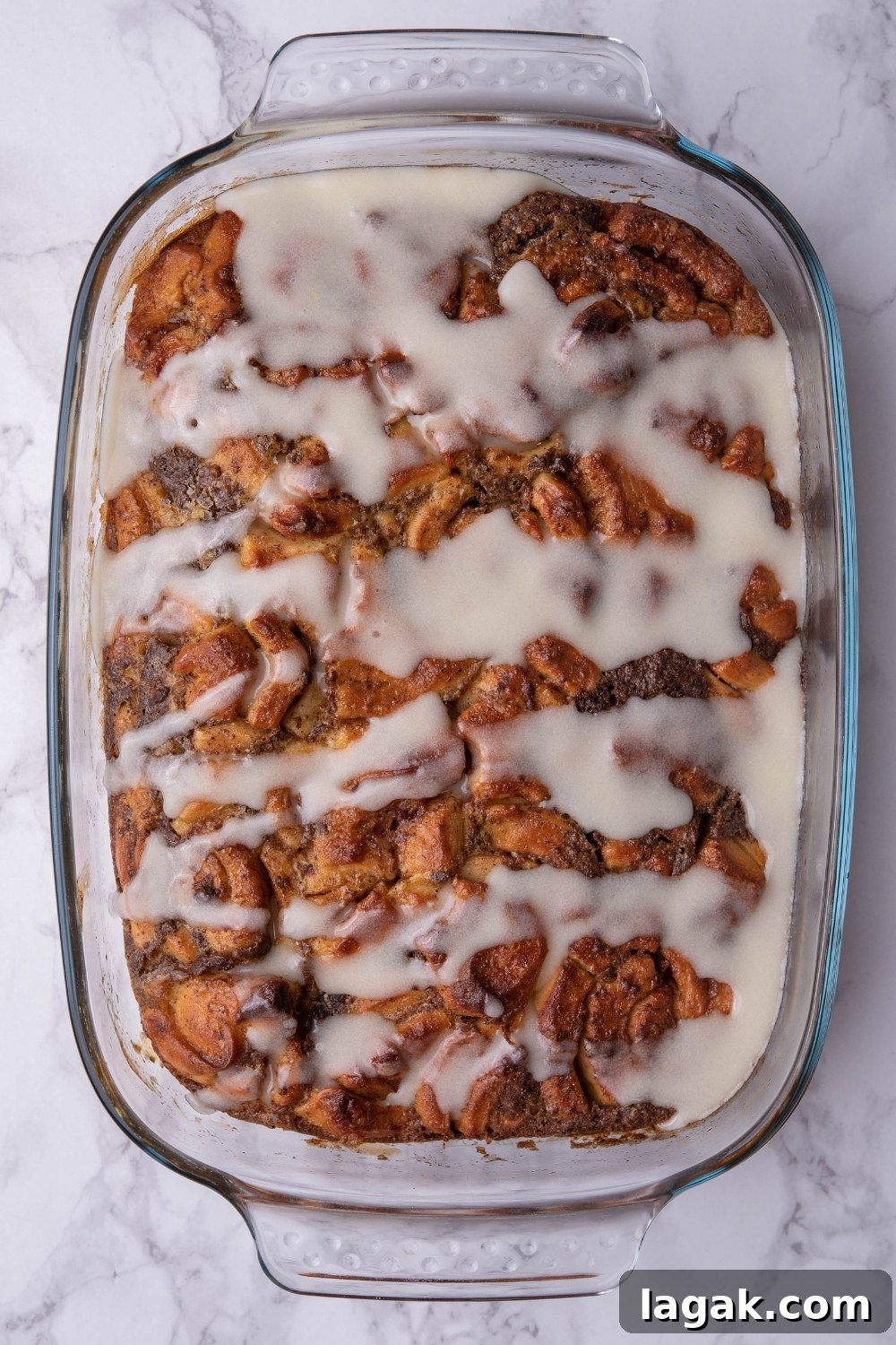 Icing on top of cinnamon roll casserole in a baking dish.