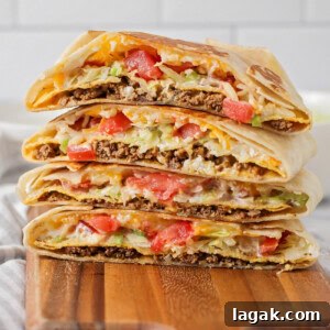 Homemade crunchwrap supremes stacked on a wooden cutting board.