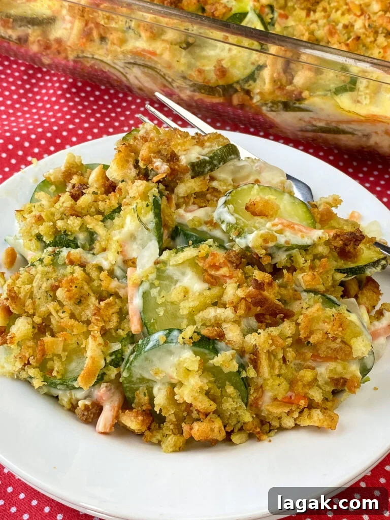 Plate of zucchini stuffing casserole with a fork on red napkin in front of baking dish full