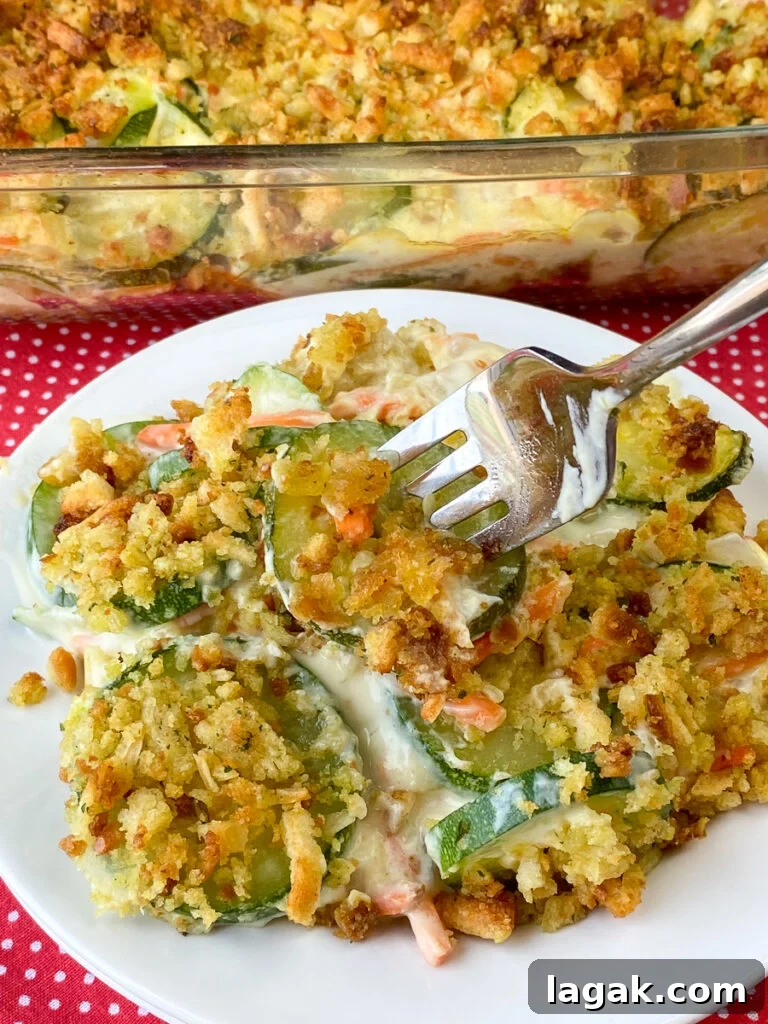 Fork in bite of zucchini with stuffing casserole recipe on a white plate