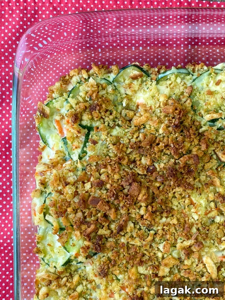 Overhead view of golden brown stuffing on top of baked zucchini casserole in a 9x13 glass dish on a red napkin
