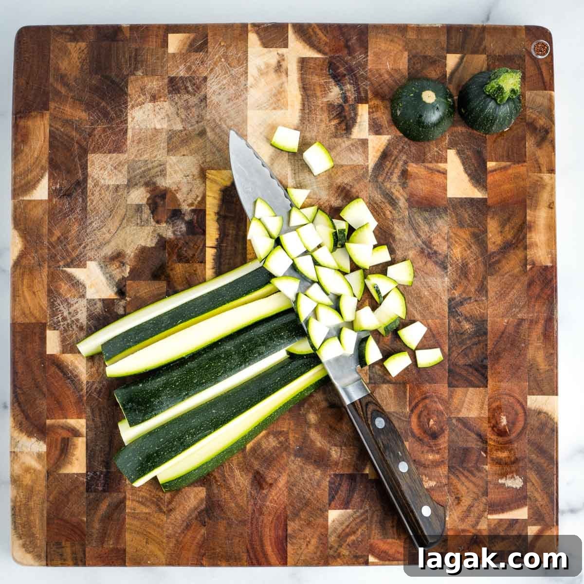 Showing how to dice a zucchini on a wooden cutting board.