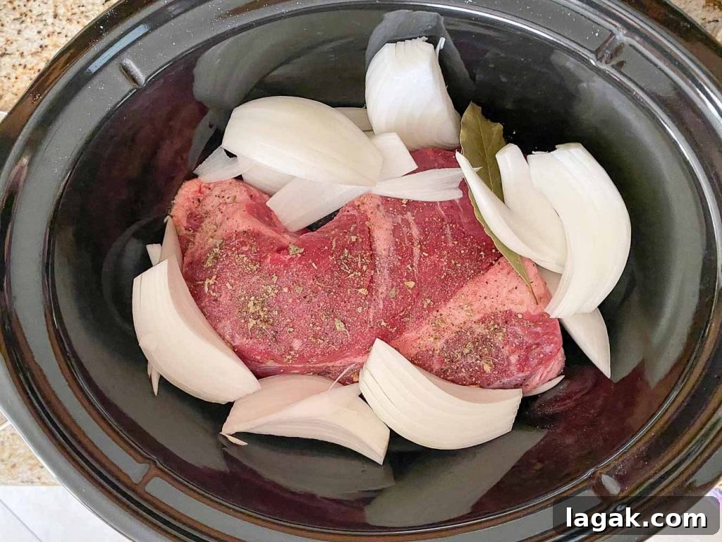 raw brisket in slow cooker with onions and spices