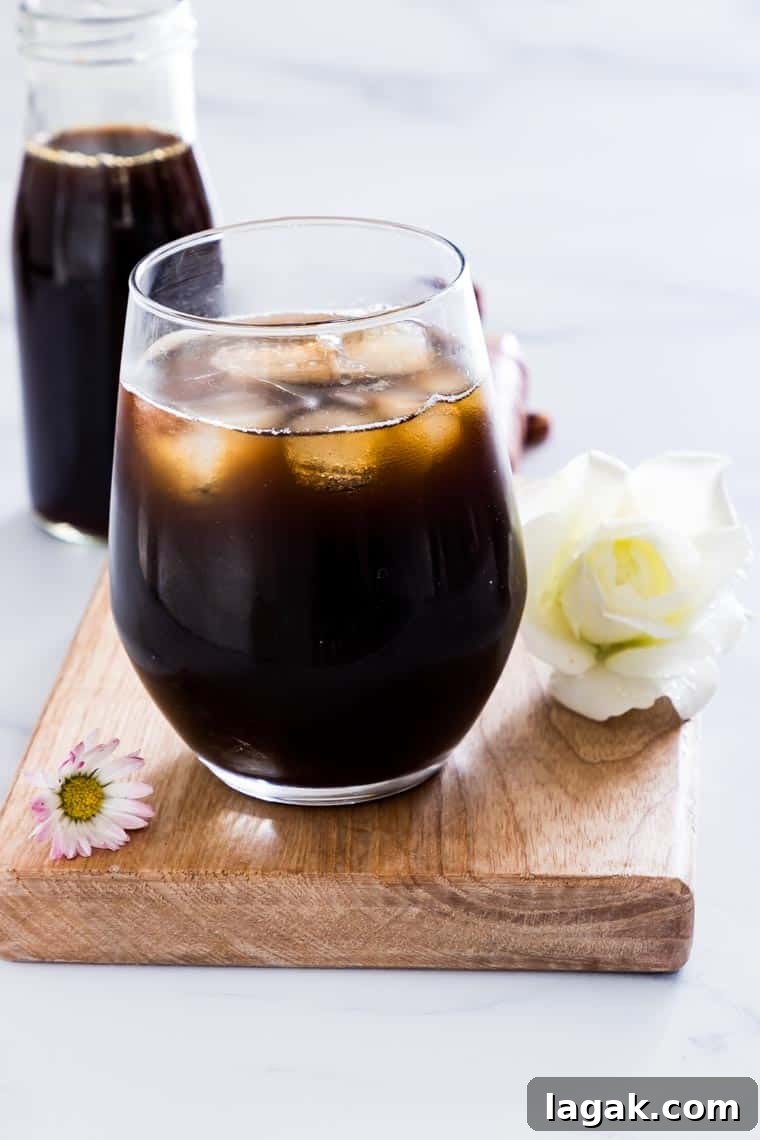 close up of instant pot iced coffee concentrate in a glass and a bottle with flowers