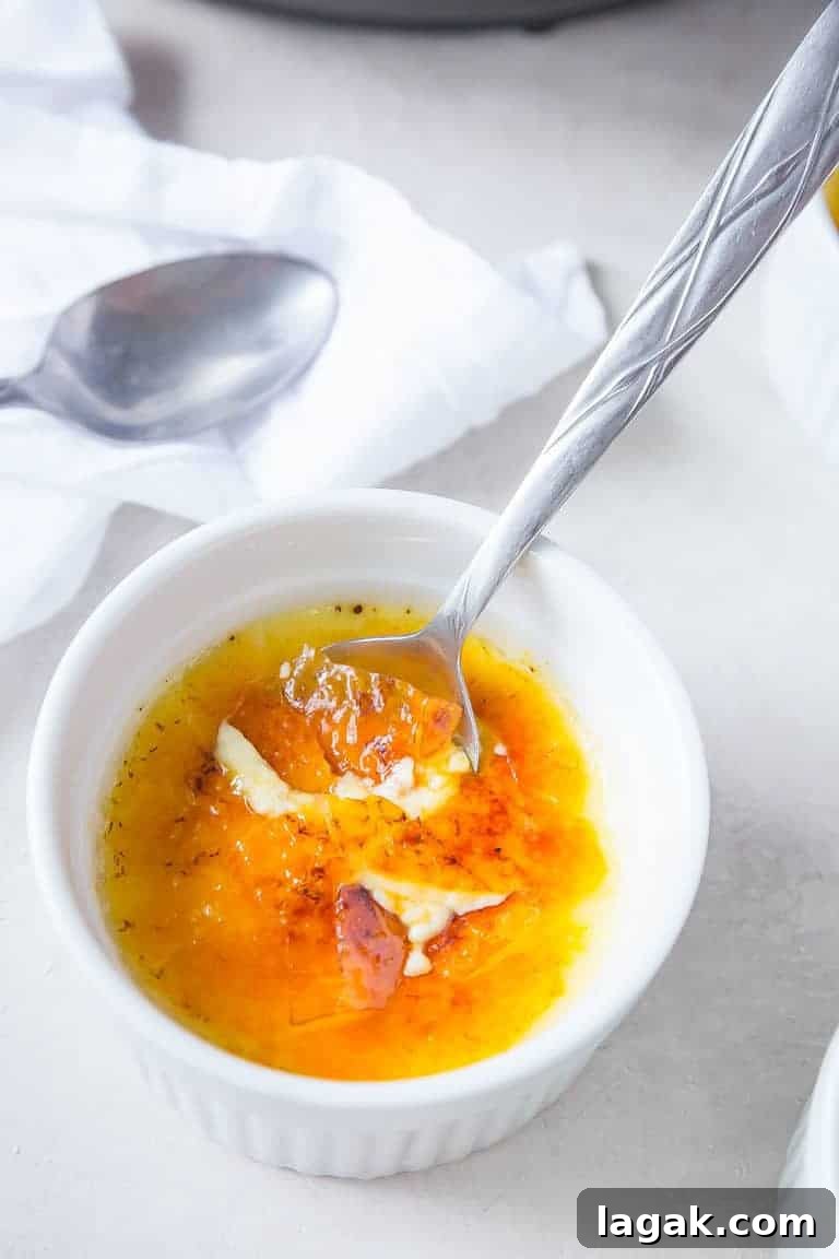 A single serving of Instant Pot Creme Brulee with a silver spoon dipped inside the ramekin