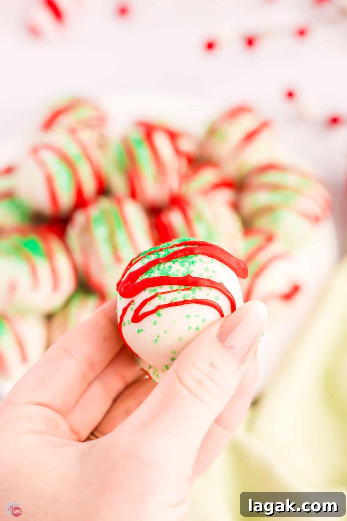 hand holding a cake ball with red stripes and green sprinkles