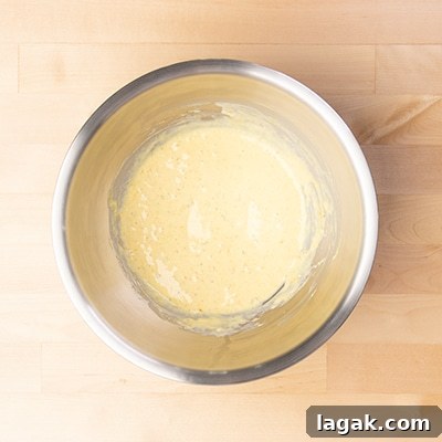 large round metal mixing bowl with light yellow liquid