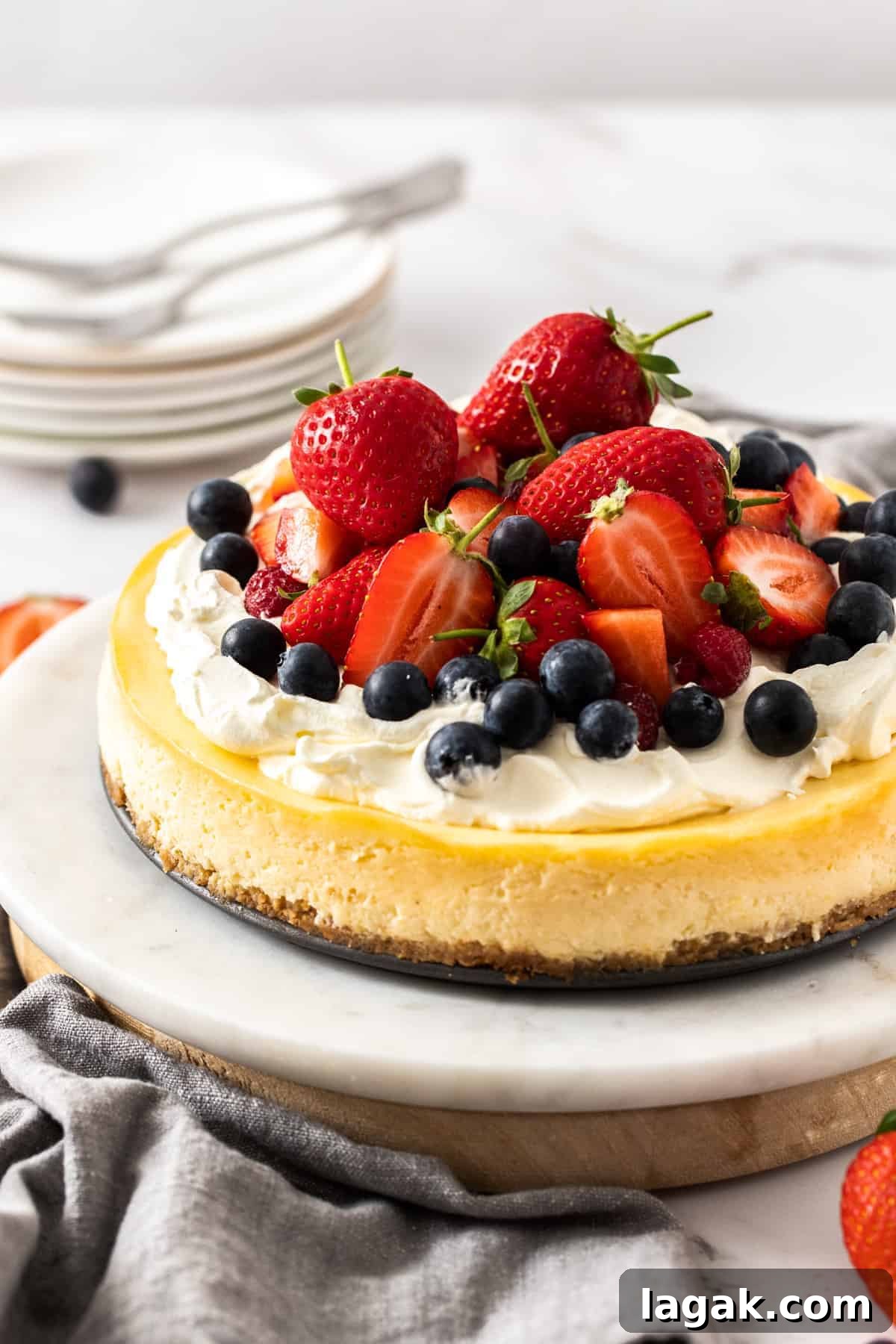 classic baked cheesecake placed on a cake stand with fruits on top